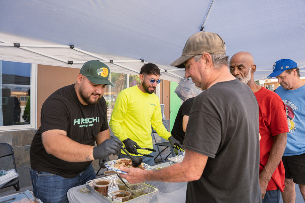 Hirschi Helping Hands are making tacos and serving them. People are lined up to get delicious tacos.