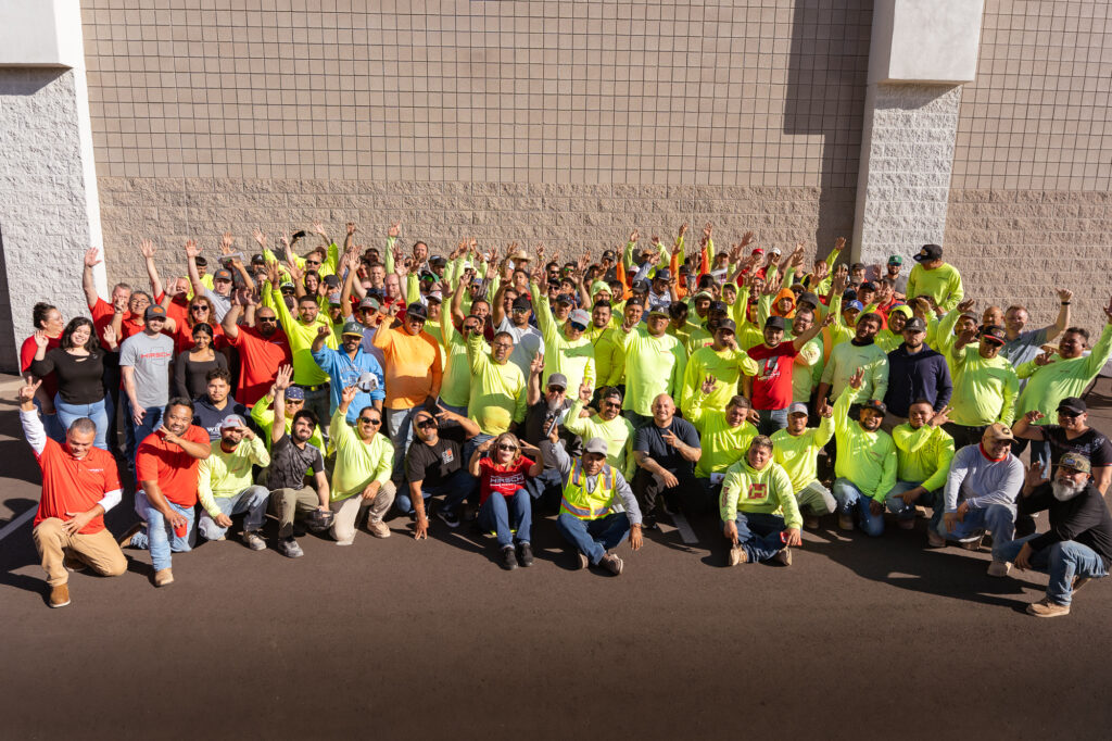 Hirschi Companies team are all standing in a group together to take a picture, all smiling and happy.